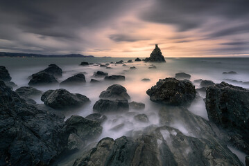 Sunset with cloudy and dramatic sky over the coast of the Cantabrian Sea on Meñakoz beach in...