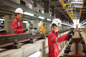 lectric train engineer employees are maintenance technicians, wearing uniforms with helmets, controlled to inspect electric train maintenance in the electric train maintenance station.