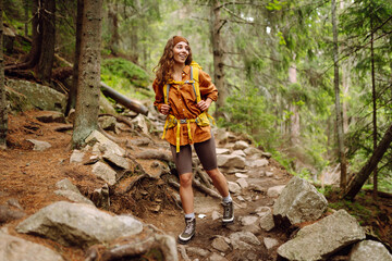 Hiking woman walk with a hiking backpack in spring green forest. Travel, nature, active lifestyle