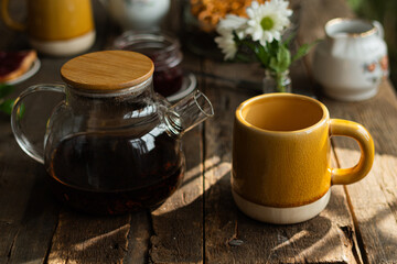 Tea mug and transparent teapot on wooden table.