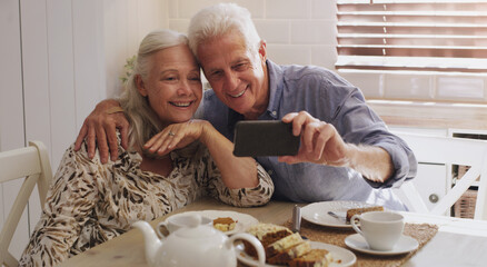 Elderly couple, love and selfie in kitchen in home with smile, retirement or bonding in marriage....