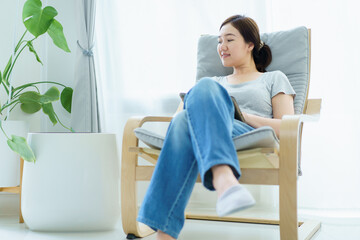 Woman using air purifier while relaxing in the living room.