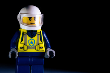 Fototapeta premium LEGO police officer in white helmet and blue uniform with yellow vest