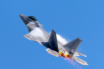 F-22 Raptor in a high G maneuver, with afterburners on and condensation clouds around the cockpit