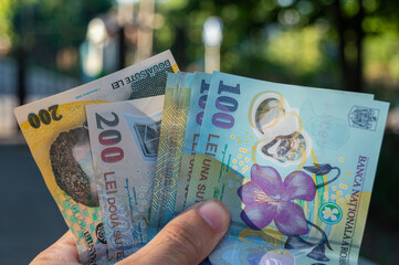 Romanian banknotes of 50, 100 and 200 lei in hand. Romanian LEI currency, close up. Romanian money...