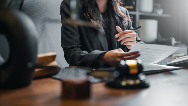 judge, lawyer, judgement, judgment, judicial, justice, law, guilty, advice, adviser. A woman is sitting at a desk with a pen and a piece of paper. She is looking at the paper and a serious mood.