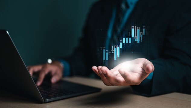 broker, chart, future, financial, graph, index, invest, management, trader, statistic. A man is holding a laptop in his hand and is looking at a graph, which could indicate a positive trend or growth.