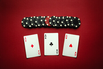 Poker game with a winning combination of three of a kind or set. Playing cards and chips on a red...
