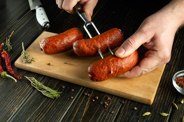 Before grilling, the cook threads the sausages onto a fork. Working environment on the table in the...