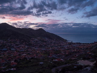 Panoramic view of town Machico before sunrise in valley on the eastern coast of Madeira island, Portugal,  cloudy early morning with harbor, beach, houses and green hills. - 790254791