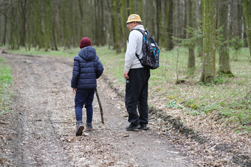 Active senior and his grandson walking, exploring the forest, turned back. Happy family active...