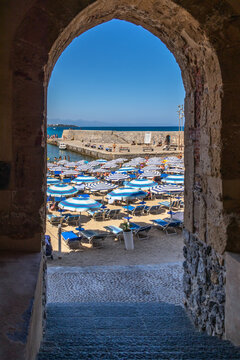 The busy beach of Cefalu shot through the arch leading to the old town