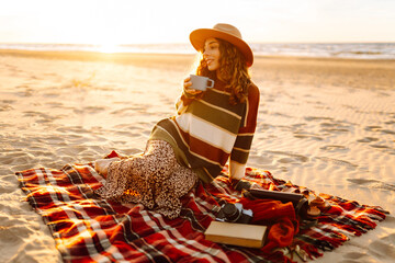 Young woman drinking morning coffee at picnic on the beach. Rest, relaxation, travel, lifestyle concept.