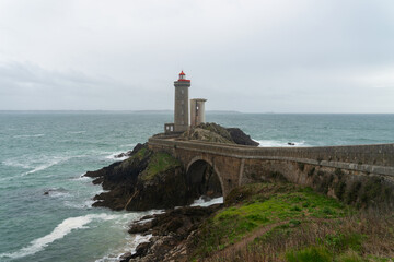 Accessible par un pont qui le relie à son îlot rocheux, le phare du Petit Minou se dresse tel un gardien solitaire au milieu des eaux tumultueuses de la Mer d'Iroise, dans le Finistère, offrant un ref