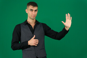 emotions of a handsome man guy on a green background chromakey close-up dark hair young man. spy