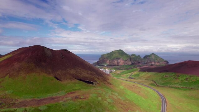 Epic Aerial Eldfell Volcanic Cone Westman Islands. Drone Over Red Ash to Lush Green Grass Town of Heimaey and Ocean Coast