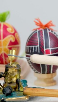 master class on making decorated eggs for Easter paints and pysanky. equipment new and old candle on white background four eggs with a pattern of black claret yellow color with a small tuft of thread
