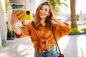 A tourist walks the streets and takes selfie using smartphone camera. Concept of positive moments,...