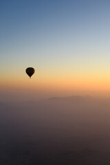 Sunrise in Morocco: A hot air balloon rises over desert dunes, illuminated by the dawn light.