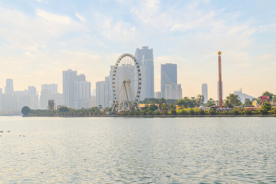 The skyline of downtown Sharjah and the Eye of the Emirates Ferris Wheel at Al Montazah Park island and amusement park, Sharjah, United Arab Emirates.	