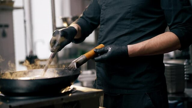 close up chef holding frying pan with ready-made noodles against the backdrop of sunset
