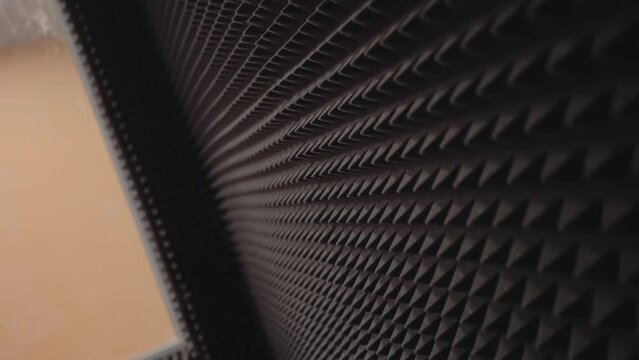 Dark soundproofing wall covering with acoustic foam rubber closeup. Well-equipped sound recording facility available in school premises