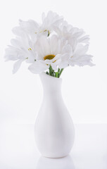 a bouquet of white daisies in a white vase