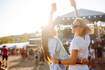 Beach party. Two young woman with beer at music festival. Summer holiday, vacation concept.
