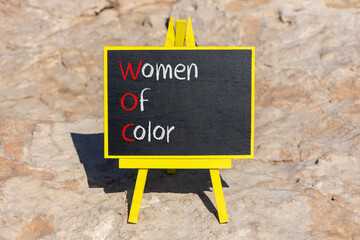 WOC women of color symbol. Concept words WOC women of color on beautiful yellow blackboard....