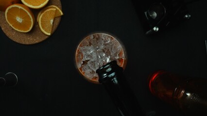 Macrography, experience the art of mixing a Negroni cocktail from a top-down perspective, adorned with a fresh vibrant orange slice, all against a dramatic black background. Alcoholic. Comestible.