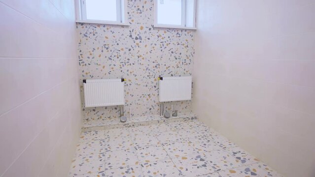 Toilet room with fresh renovation in light colours. Toilet equipped with modern heating batteries to maintain comfortable temperature in premise