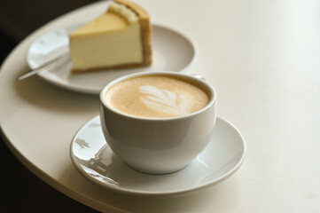 A cup of hot cappuccino latte coffee with a piece of cake for breakfast.