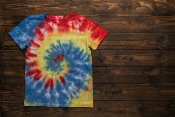 Colorful tie dye T-shirt on a dark wooden background.