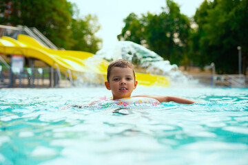 A little boy swimming in a beautiful blue pool with an inflatable circle. Child drowning in the pool	 - 790318110