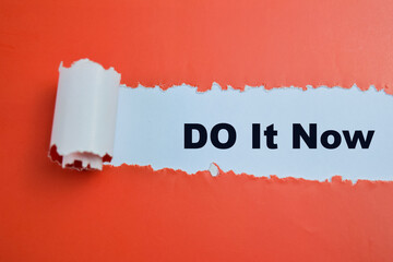 Concept of Do It Now Text written in torn paper.