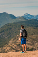 Fototapeta premium hiker with backpack standing on mountain peak overlooking a stunning mountain range