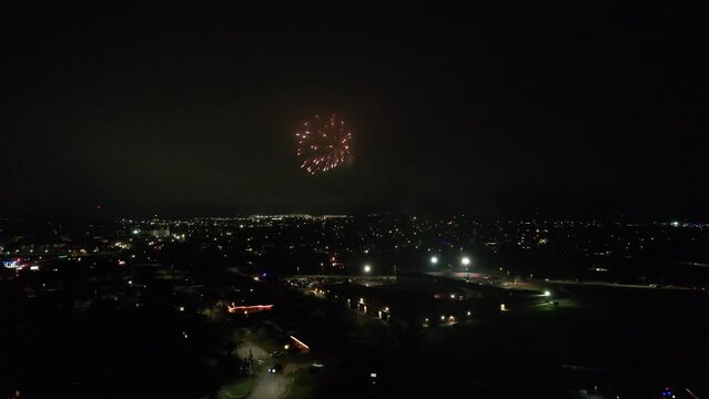 Drone night view of fireworks in dark sky over illuminated city