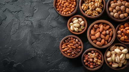 Fotobehang Mixed nuts in wooden bowls on black stone table almonds pistachio walnuts cashew hazelnut top view nut photo, generated with AI © sch_ai