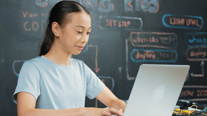 Smart girl programing system by using laptop at blackboard. Highschool student writing engineering...