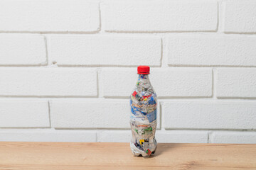 one eco brick PET bottle stuffed with plastic waste with white brick wall