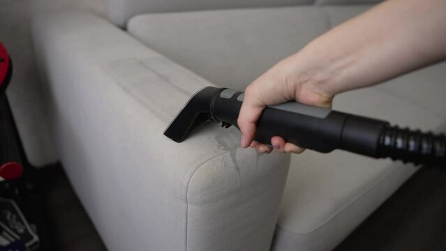 Close-up of sofa cleaning equipment. A woman cleans a dirty stain on the sofa. Professional Housekeeping Cleaning Services. Cleaning a sofa with Karcher.