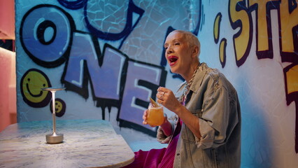 Fototapeta premium Joyful woman singing cafe with cocktail. Carefree trendy senior dancing club