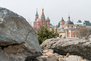 Side view from public park of Church of Barbara on Varvarka, Saint Basil's Cathedral and Spasskaya Tower of Moscow Kremlin over large stones in a spring day. Selective focus. Russian culture theme. - obrazy, fototapety, plakaty