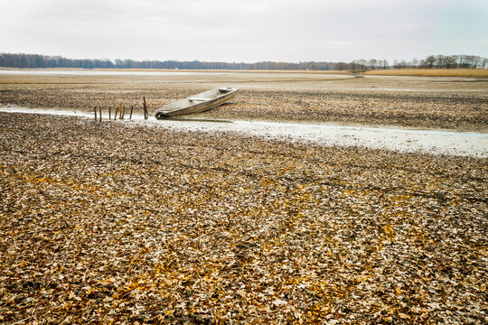 White boat od dried bottom of a lake with mud