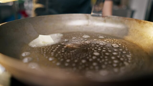 close-up of a frying pan in a professional kitchen in which piece of butter is heated
