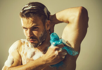 Sexy bearded man washing muscular body with moisturizing gel. Handsome man with naked torso taking...