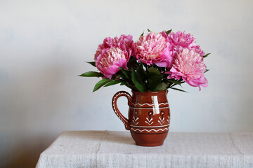 Pink Peonies in A Clay Jug On A Light Background. Garden Flowers.