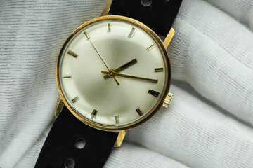 Watchmaker in white gloves proudly presents a handcrafted gold watch from the 1960s - a masterpiece...