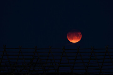 Full moon with orange glow and faint wooden fence