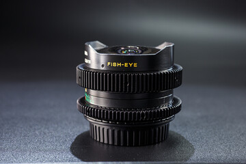Black fisheye camera lens featured on vintage photographic gear stack, sharp engraving and textured...